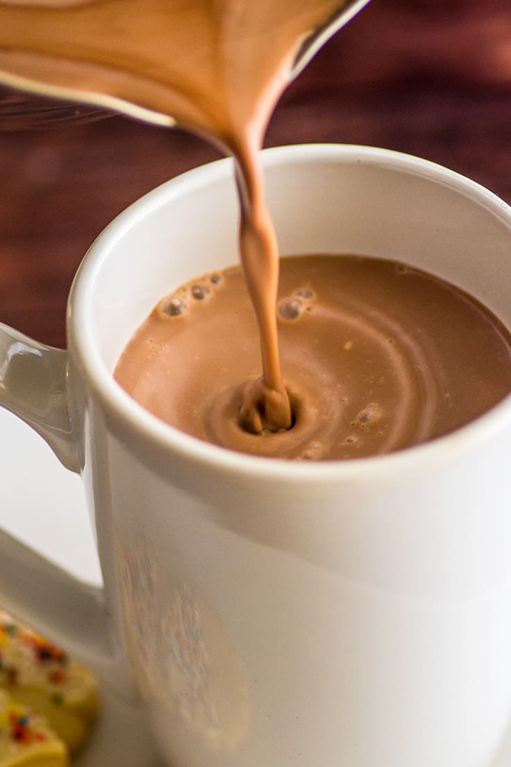 Homemade hot chocolate being poured into a white mug.