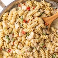 Spoon scooping creamy chicken pasta with bell peppers.