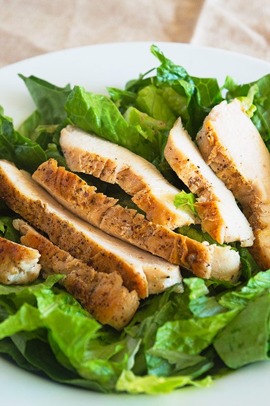 Sliced cooked chicken breast on romaine lettuce.