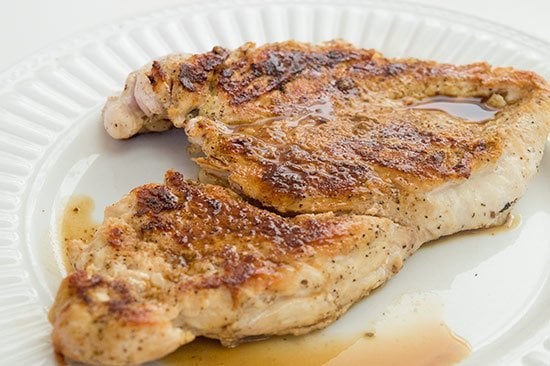 Cooked chicken breast on a white plate.