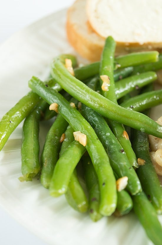 Butter and garlic green beans on a white plate.