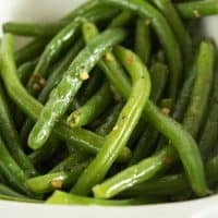 Butter and garlic green beans in a white dish.