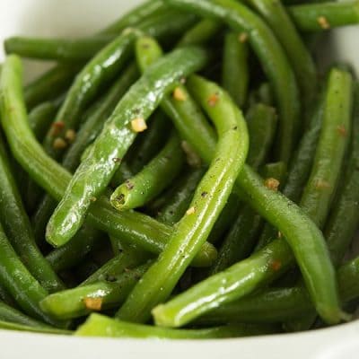 Butter and garlic green beans in a white dish.