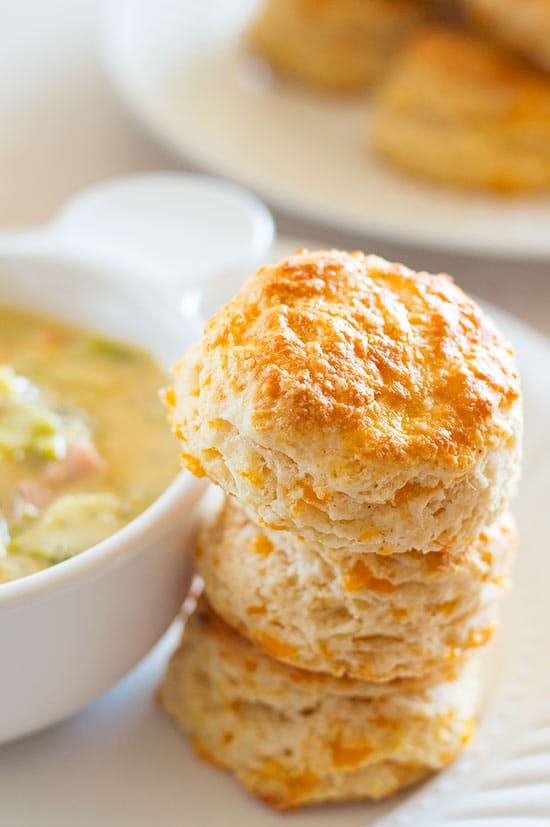Cheddar Cheese Scones stacked next to a bowl of soup.
