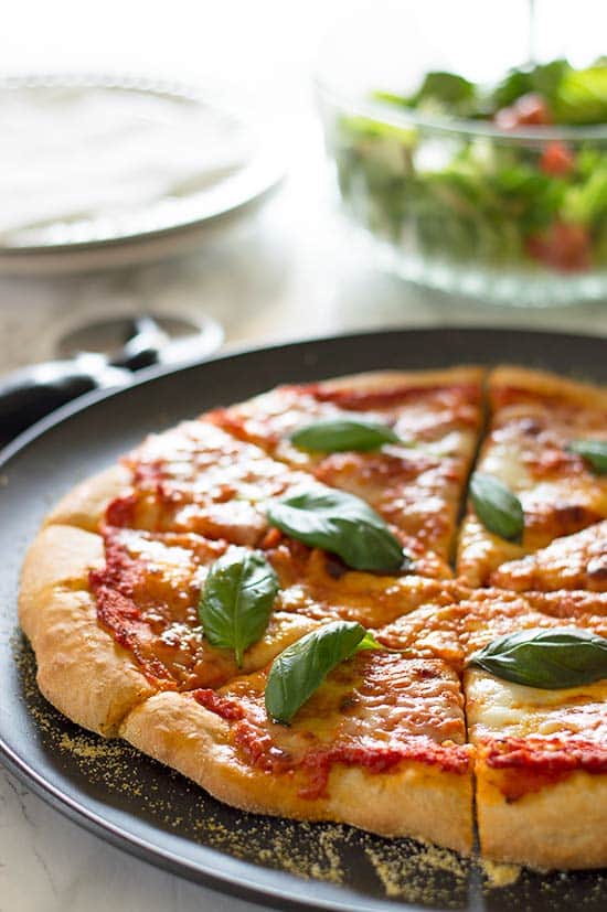 Margherita Pizza on a pizza tray with salad.