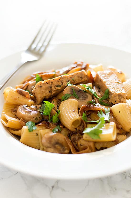 Lightened Up Copycat Carmela's Chicken - Chicken, mushrooms, and delicious caramelized onions cooked up in a wine and cream sauce and served over rigatoni. A lightened up version of the Macaroni Grill favorite. Recipe includes nutritional information, make-ahead and low-yield instructions. From BakingMischief.com