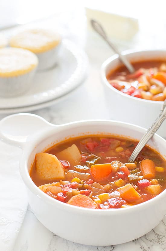 Bowls of Vegan Vegetable Stew on a table with cornbread muffins.