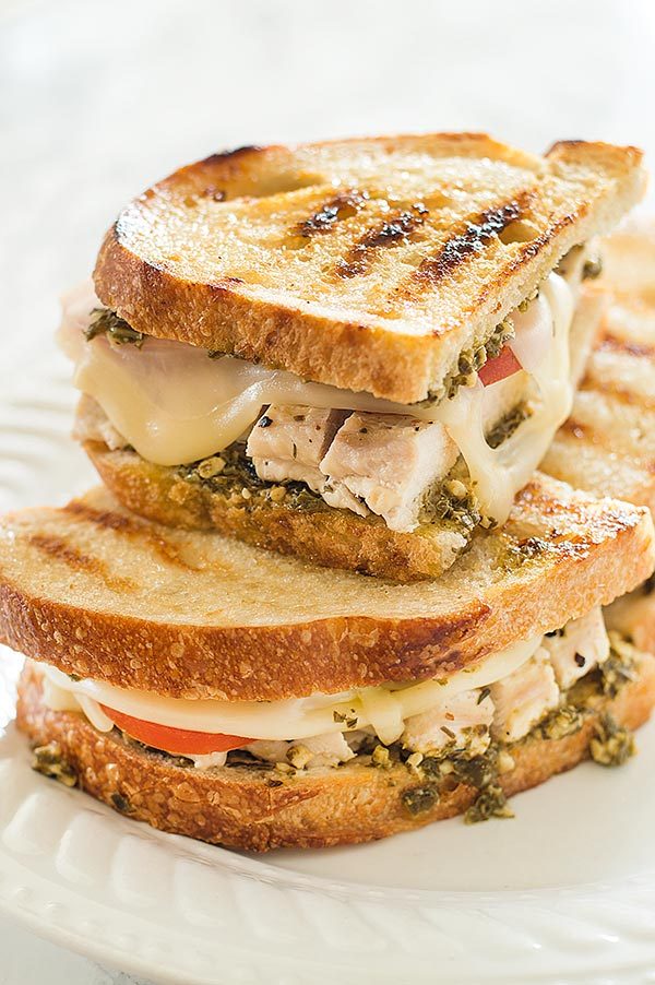 Pesto chicken sandwiches on sourdough on a white plate.
