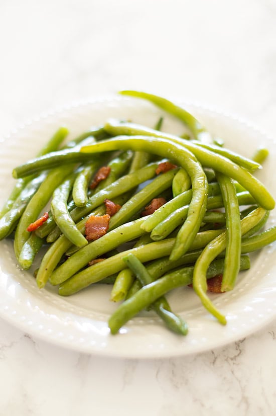 Bacon green beans on a white plate.