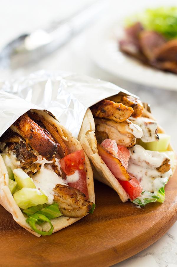 Easy chicken shawarma with yogurt shawarma sauce wrapped in foil on a wooden plate.