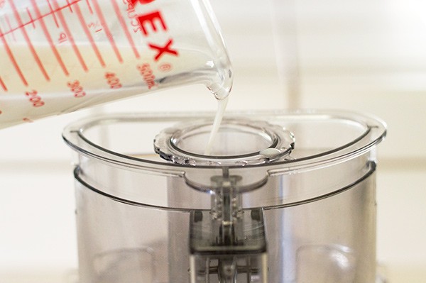 Buttermilk being poured into food processor for pie dough.