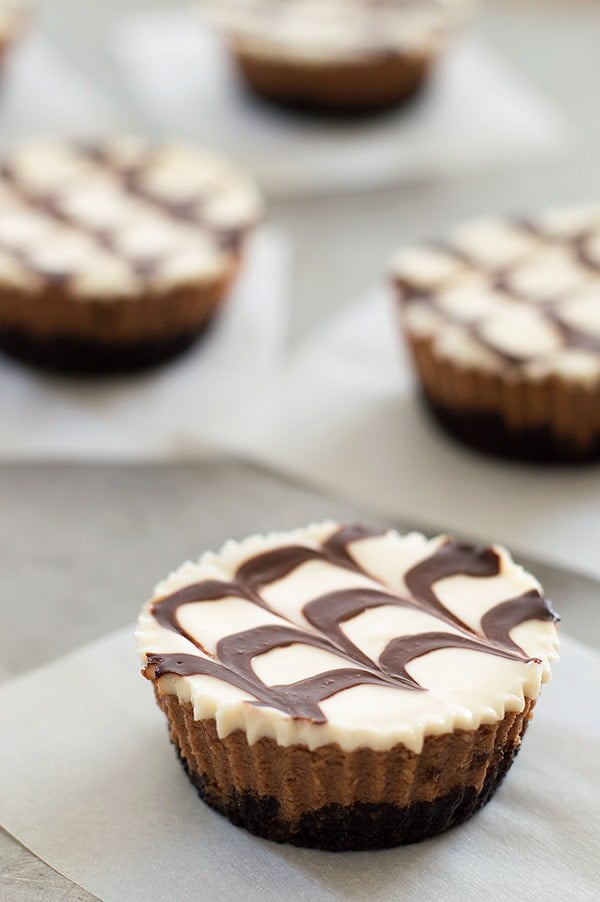 Mini mocha and Kahlua cheesecakes with a crunchy Oreo cookie base, cool sour cream topping, and fudge sauce. Recipe includes small-batch instructions and nutritional information. From BakingMischief.com