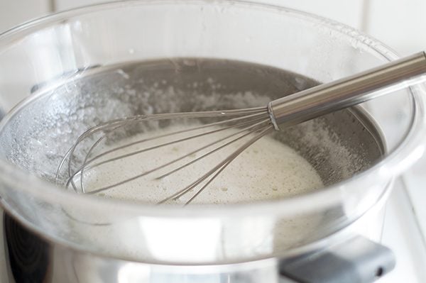 Eggs and sugar being heated over double boiler for marshmallow frosting.