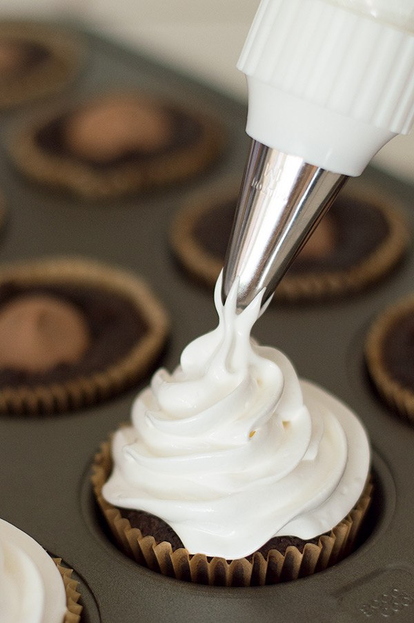 Cupcake being frosted with marshmallow frosting.