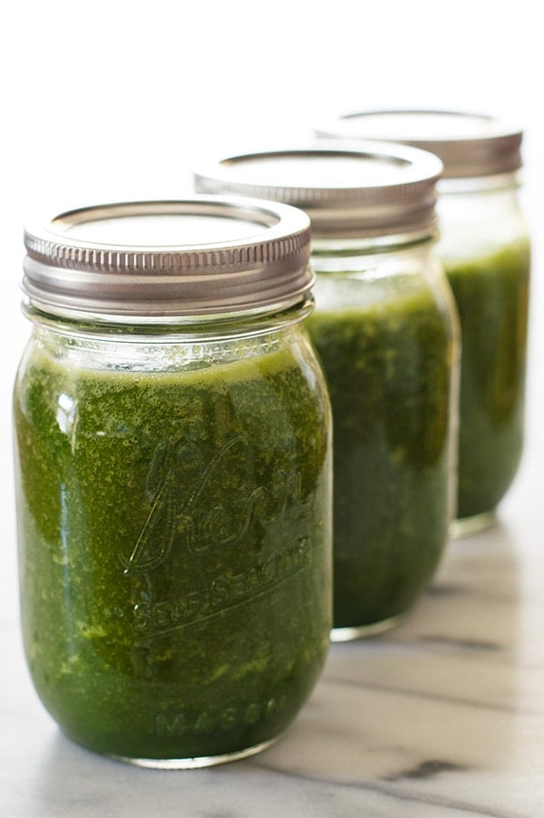 Green smoothies in mason jars lined up on a counter.