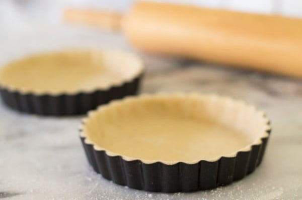 Unbaked tart shells in tart molds.