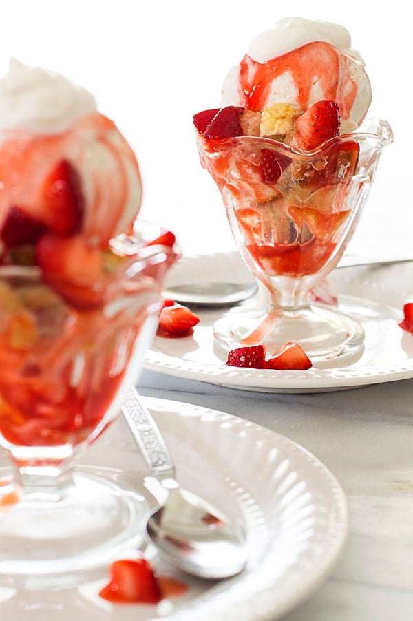 Strawberry shortcake sundaes with whipped cream in sundae cups.