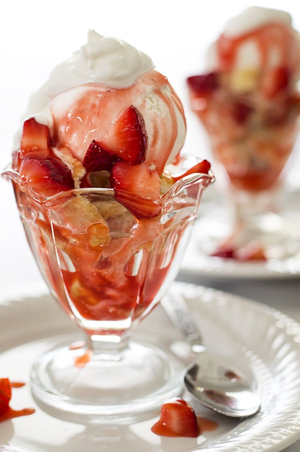 Two strawberry shortcake sundaes in glass sundae cups.