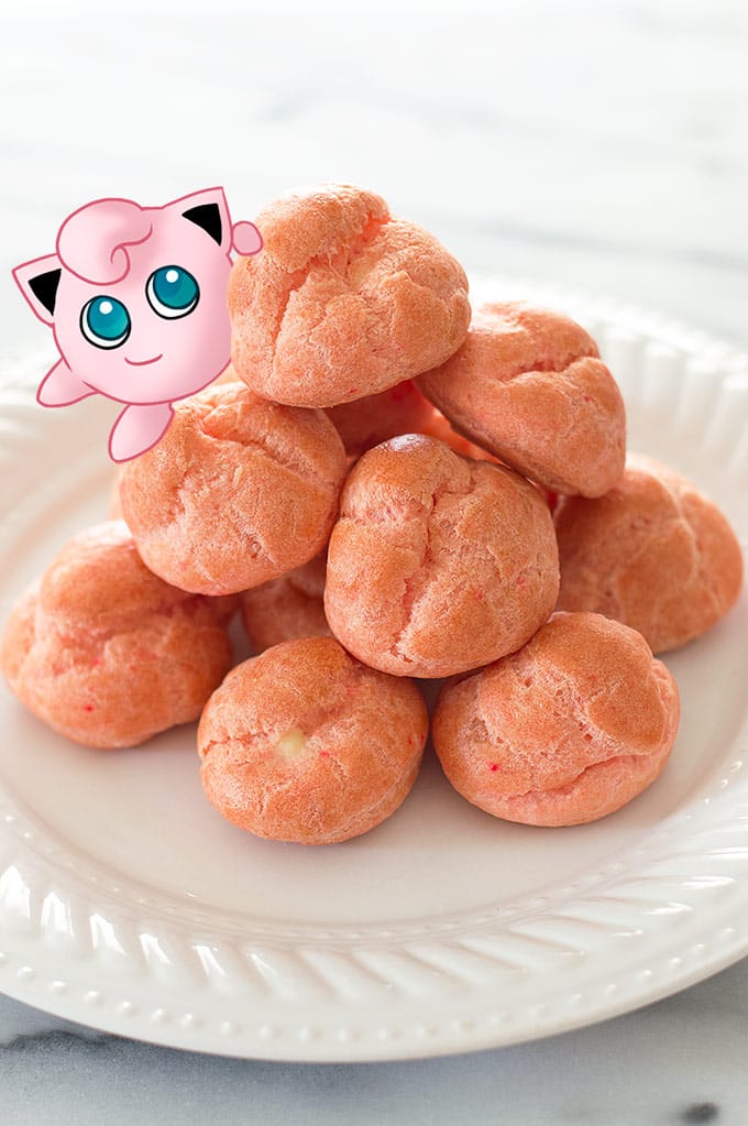 Pile of pink cream puffs on a plate with a jigglypuff on top.