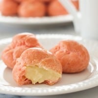Pink Cream Puffs filled with a rich vanilla pastry cream. So cute and delicious you'll want to keep them all to yourself. Recipe includes nutritional information. From BakingMischief.com