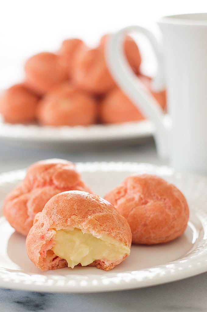 Pink Cream Puffs filled with a rich vanilla pastry cream. So cute and delicious you'll want to keep them all to yourself. Recipe includes nutritional information. From BakingMischief.com