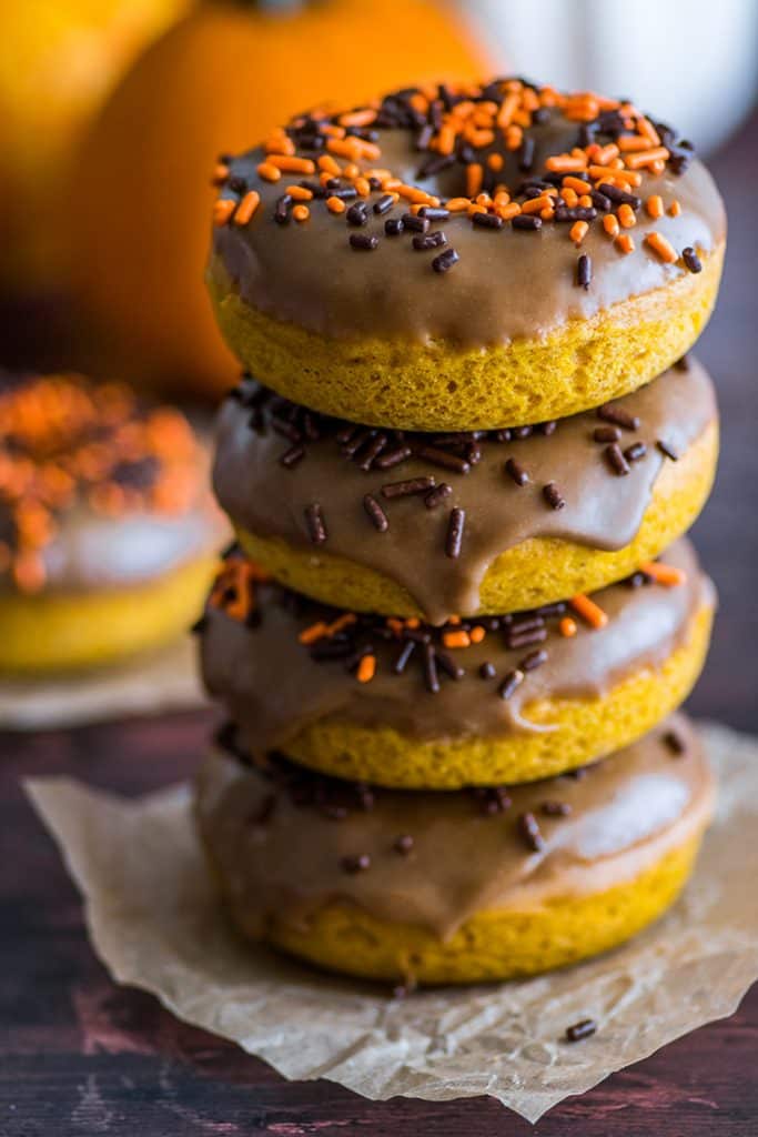 Photo of pumpkin donuts make with pumpkin puree stacked on parchment paper.