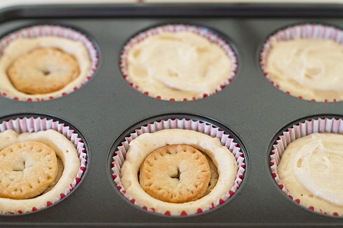 Mini apple pies being pressed into apple pie cupcake batter.