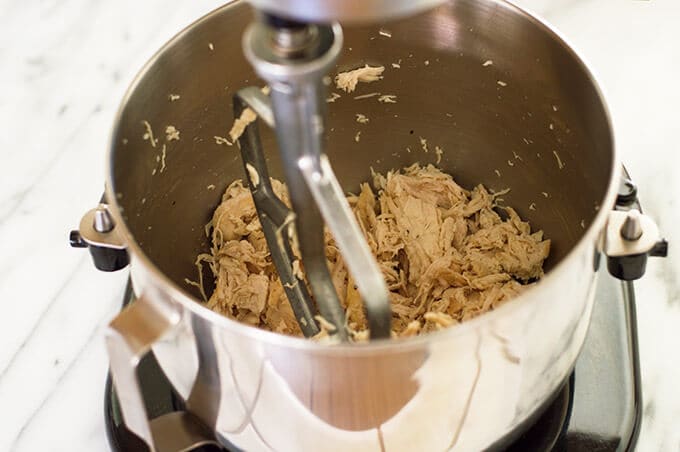 Chicken being shredded in a stand mixer.