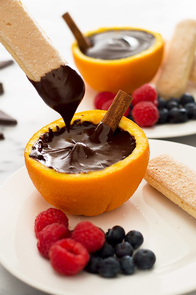 Lady finger being dipped into sanguinaccio dolce.