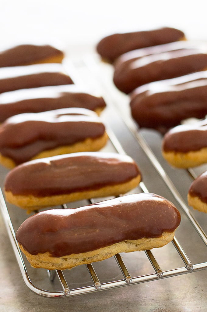 Glazed pumpkin eclairs on a cooling rack.