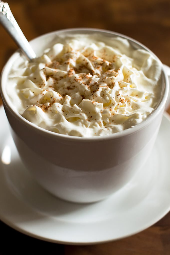 Eggnog latte with whipped cream in a white mug.