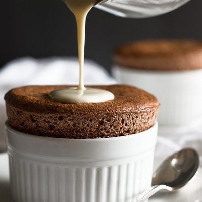 Creme anglaise being poured over chocolate souffle.