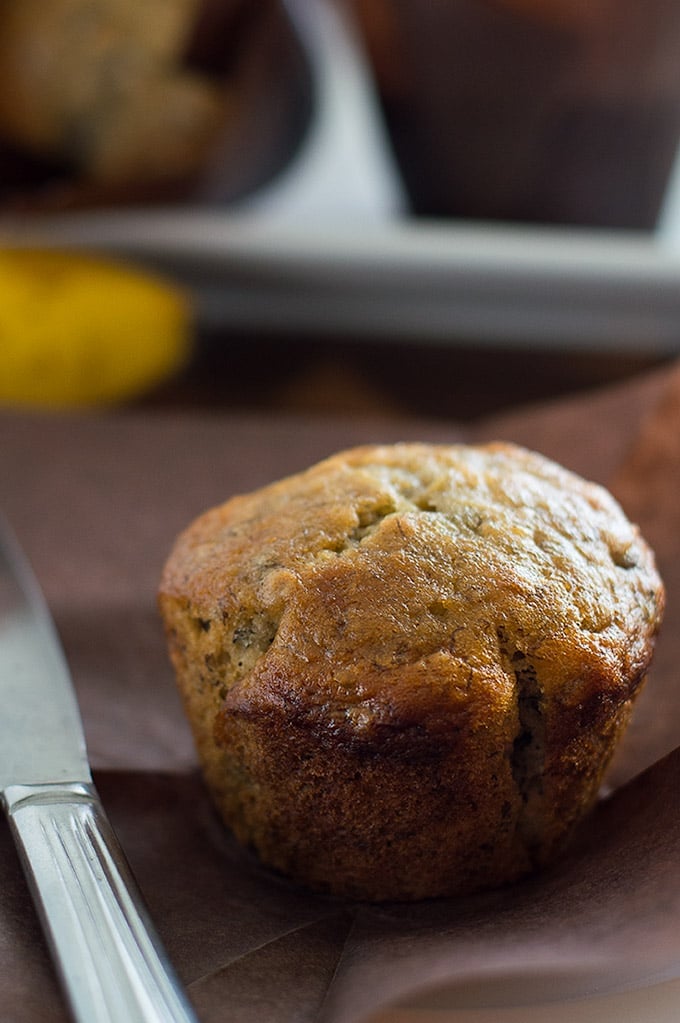 Small-batch banana muffins on a table with one unwrapped.