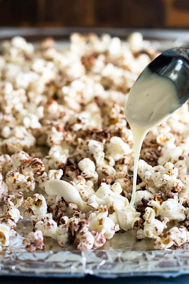 White chocolate being drizzled over Cinnamon Bun Popcorn.