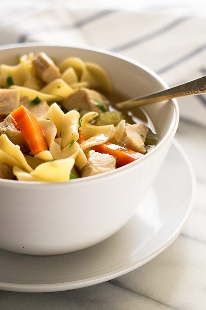 Close up image of chicken noodle soup for one in a white bowl.