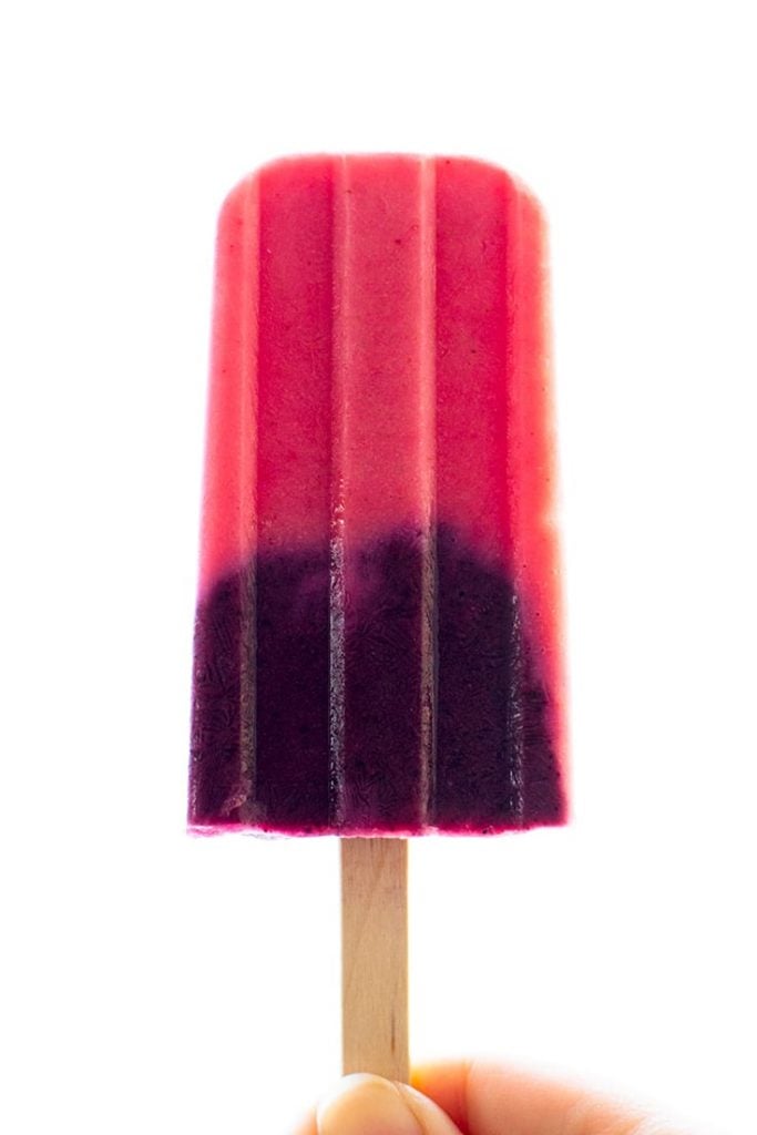 Picture of hand holding a strawberry and blueberry smoothie popsicle.