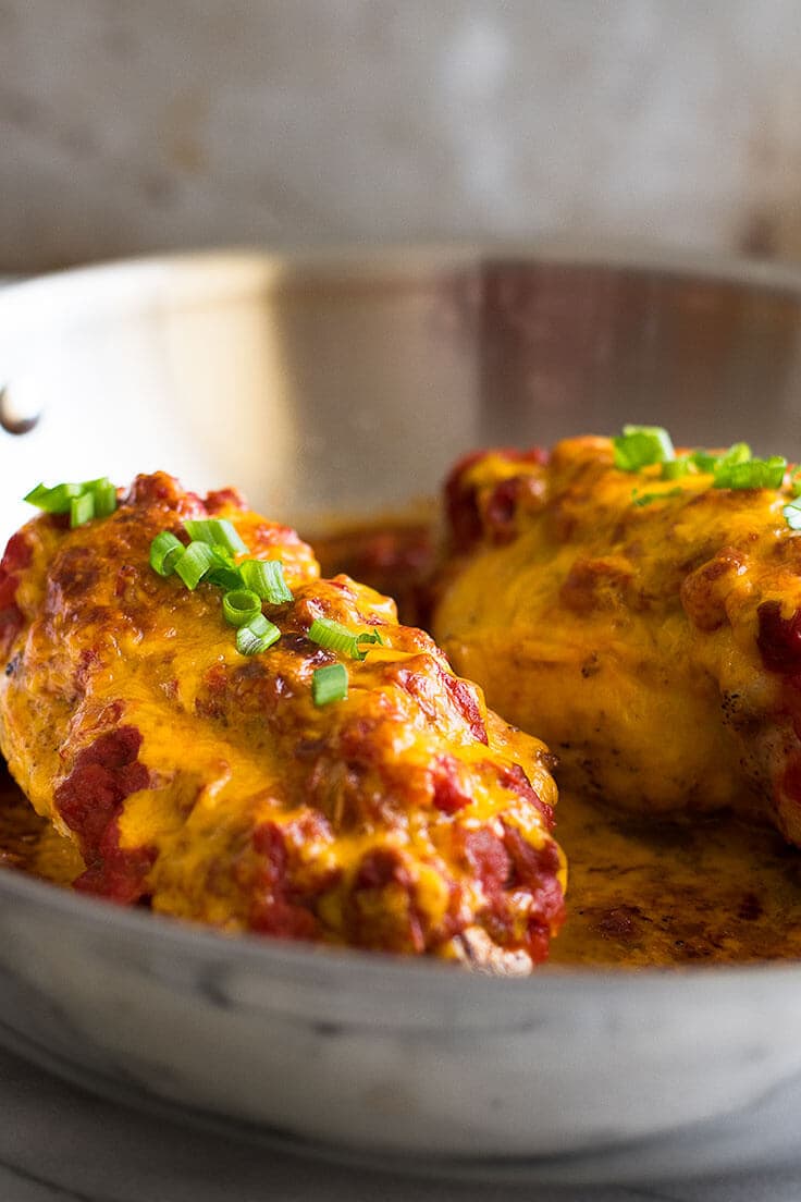 Salsa chicken with green onions in a skillet.