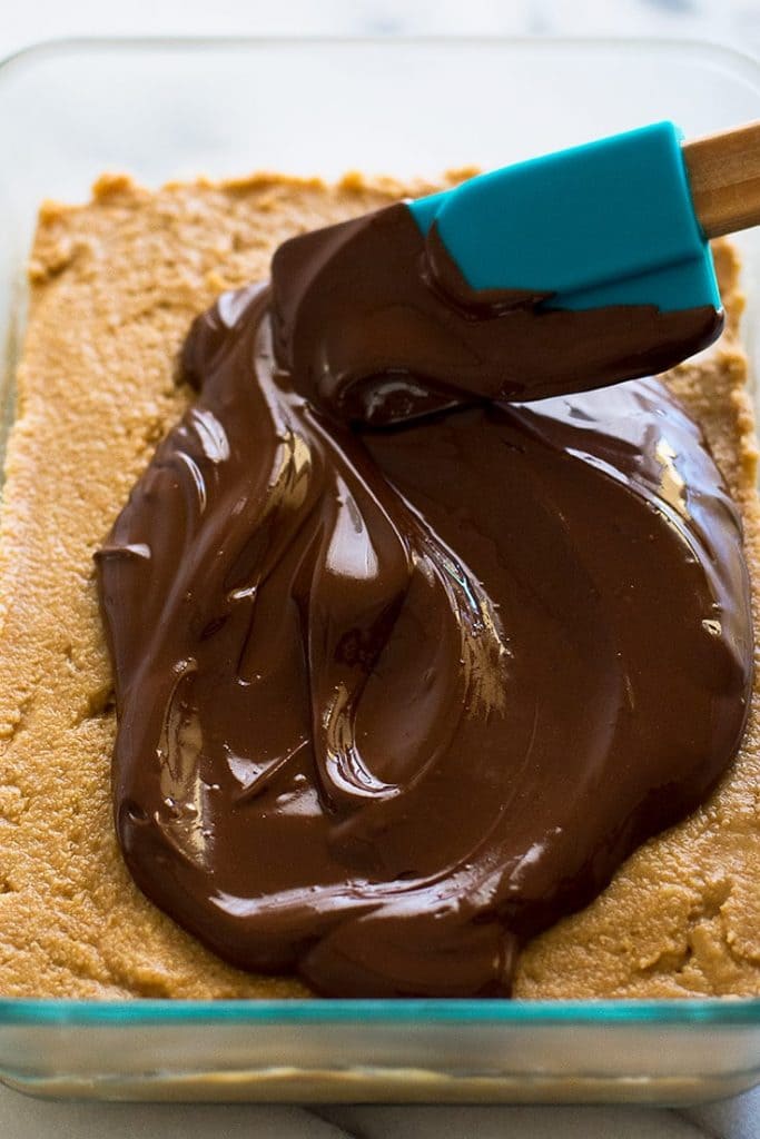 Process photo for peanut butter bars of melted chocolate being spread over peanut butter base.