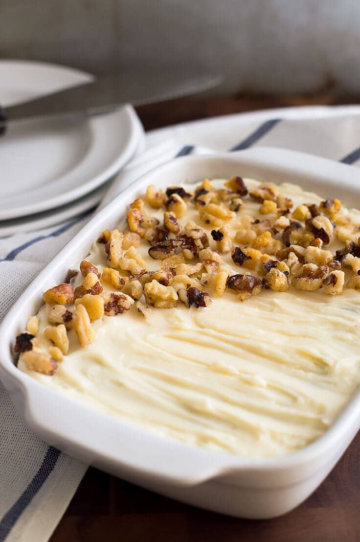 Photo of small carrot cake with cream cheese frosting in a white dish.