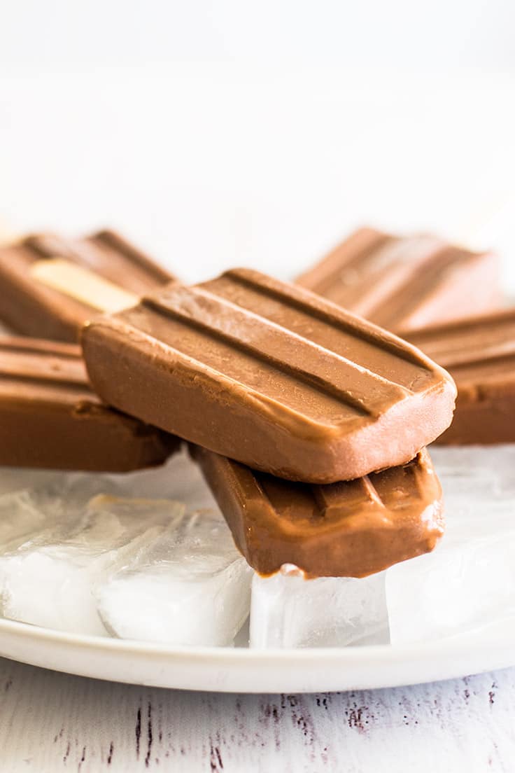 Homemade pudding pops stacked on a plate of ice.
