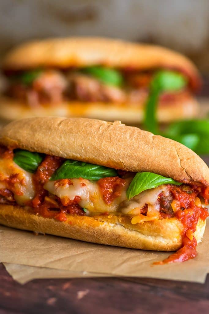 Meatball sandwiches with marinara sauce on parchment paper.