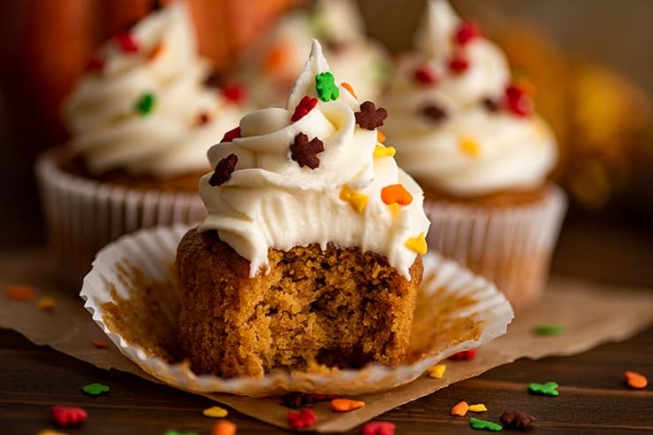 Pumpkin cupcake with cream cheese frosting with a bite out of it.