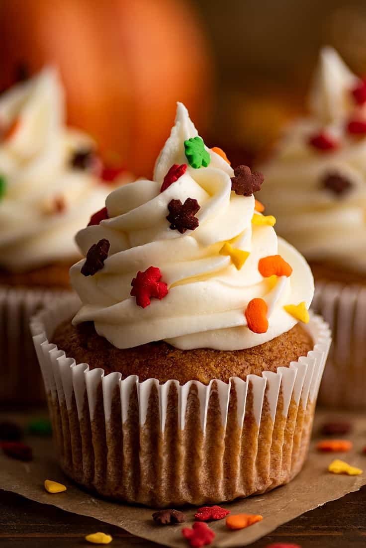 Small-batch pumpkin cupcakes with fall sprinkles on parchment paper.