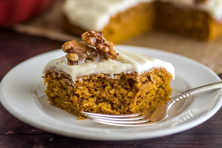 Mini Pumpkin Cake with cream cheese frosting and candied walnuts with a bite out of it.
