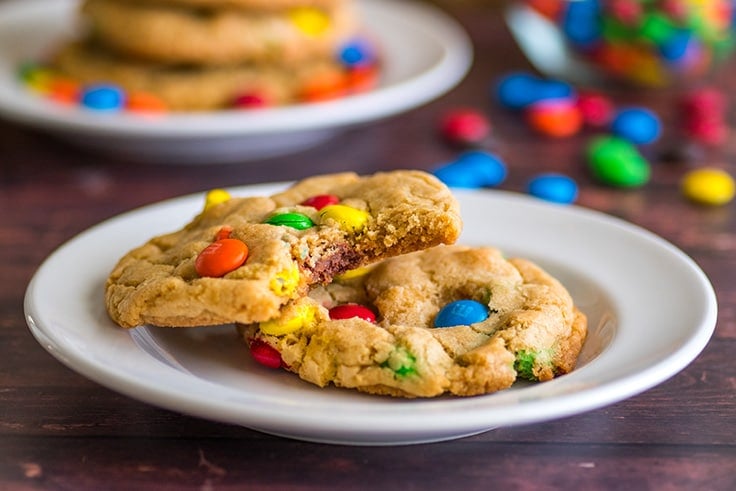 Two M&M cookies on a white plate.