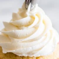 Small-batch vanilla frosting being piped onto a cupcake.