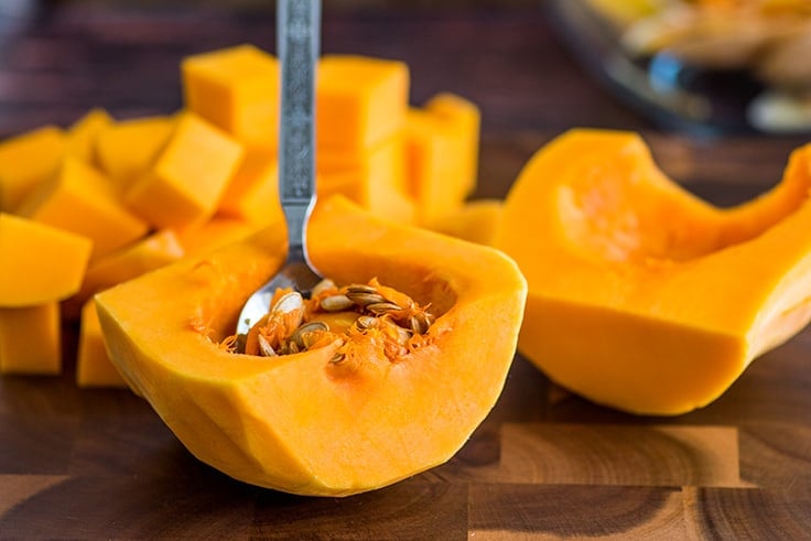 Seeds being scooped out of butternut squash.