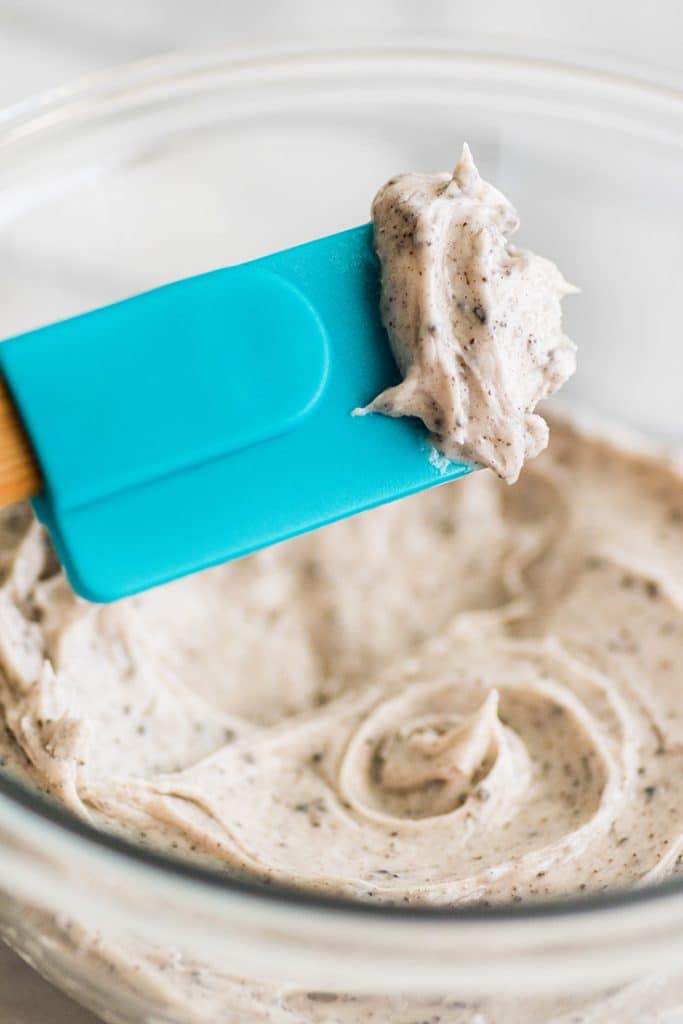 Small-batch cookies and cream frosting being scooped out of a bowl.