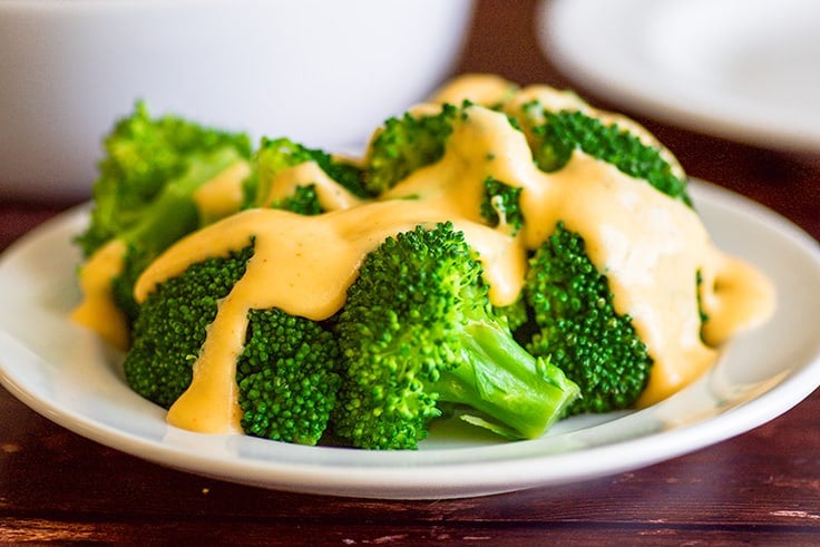 This fabulous creamy homemade cheese sauce is super easy and perfect for dipping and drizzling. | #CheeseSauce | #broccoli | #SideDish | #snack | Wide photo of cheese sauce poured over broccoli.