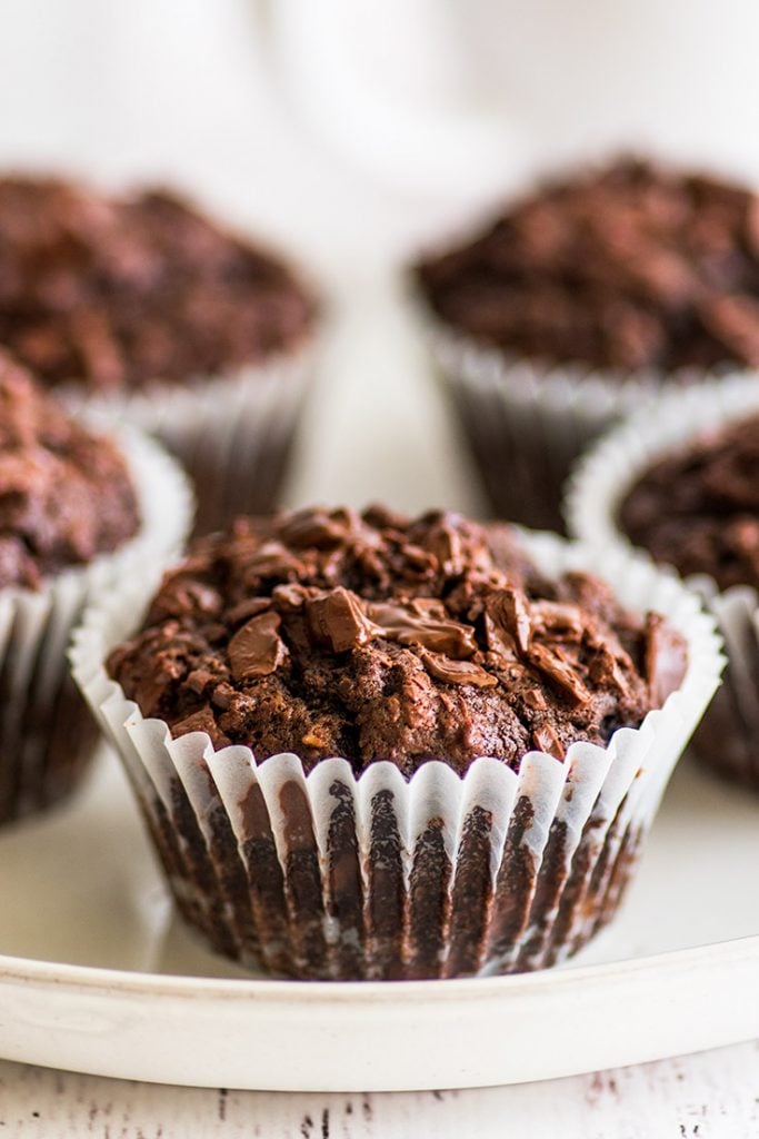 The BEST Chocolate Banana Muffins you'll ever eat. This easy small-batch recipe makes 5 muffins. You just need one ripe banana and one bowl, and you can be pulling these out of your oven in less than half an hour. | #breakfast | #chocolate | #bananamuffins | #breakfastfortwo | Vertical picture of five Small-batch Chocolate Banana Muffins on a plate.